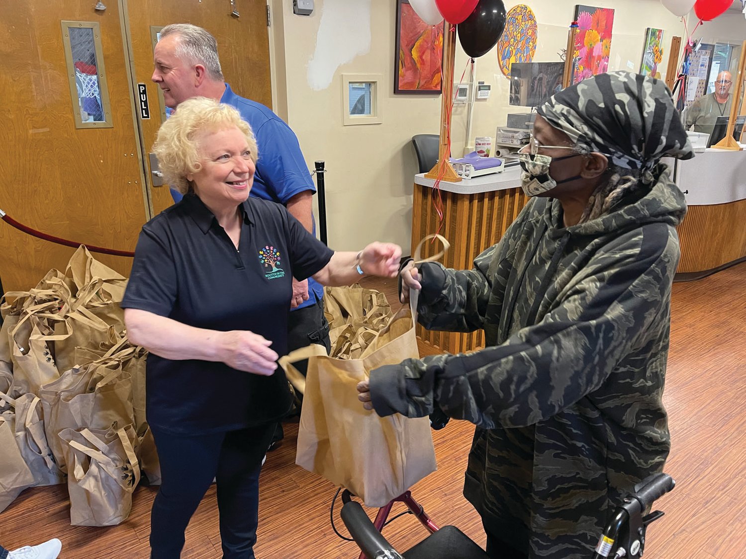 REASON TO SMILE: Rita Penzo, a volunteer at the Cranston Senior Enrichment Center, handed out gift bags to the seniors arriving for Tuesday’s event. “It’s been tough,” she said of the past year.